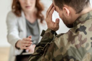 A soldier sits as their therapist reaches over to them in support. This could represent the support that a PTSD therapist in West Des Moines, IA can provide. Contact a trauma therapist for support with trauma therapy and PTSD treatment in West Des Moines, IA. We offer EMDR therapy and other services, so call today!