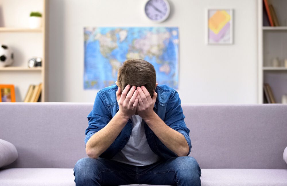 EMDR Therapy - A man holds his head in his hands as they struggle with their thoughts. Depression treatment in West Des Moines, IA can offer support via online therapy for depression in Iowa and in West Des Moines, IA. Contact a depression therapist in West Des Moines, IA for support today! 50266