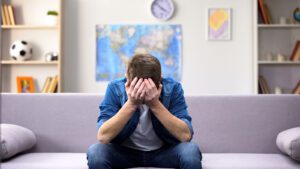 EMDR Therapy - A man holds his head in his hands as they struggle with their thoughts. Depression treatment in West Des Moines, IA can offer support via online therapy for depression in Iowa and in West Des Moines, IA. Contact a depression therapist in West Des Moines, IA for support today! 50266