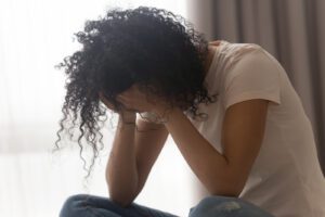 An upset woman hangs her head with covering her face. A depression therapist in West Des Moines, IA can offer support with depression treatment. Learn more about online therapy for depression in Iowa today. 50266