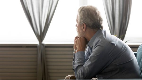 A man with depression sits as he looks pensively out the window. Individual and couples therapy can help in West Des Moines, IA can help you improve communication.