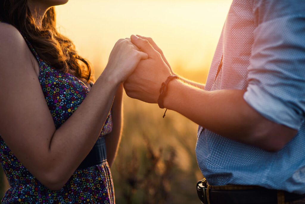 A close up of a couple holding hands as the sun sets between them. Online marriage counseling in West Des Moines, IA can offer relationship support. Contact an online marriage counselor in West Des Moines, IA to learn more about online couples counseling and more! 50266