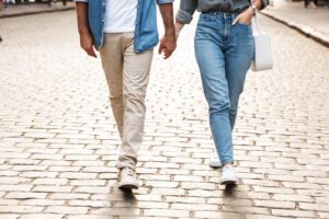 A couple hold hands as they walk down a stone street. Online marriage counseling in Iowa can offer support in creating stronger bonds. Contact an online couples counselor to learn more about online marriage counseling in Iowa today! 50266