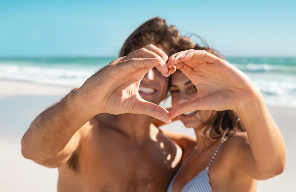 A couple standing on the beach make a heart shape with their hands. This could represent how sexual health counselling in West Des Moines, IA can offer support for couples everywhere! Learn more about sex counseling in West Des Moines, IA by contacting a sexual health counselor today! 50266